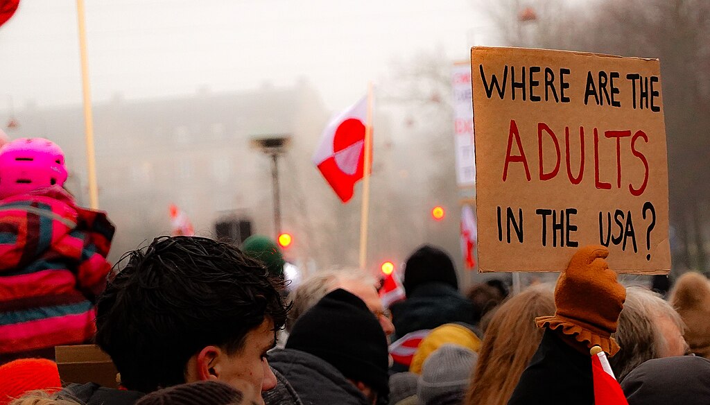Protesters at a Hands off Greenland demonstration in Copenhagen, including a placard reading Where are the adults in the USA and Greenlandic flags in the crowd.